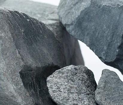 Grå stein med store størrelsesforskjeller. En stor stein og andre i andre varierende størrelser. Foto. 